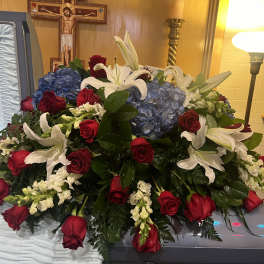 Casket spray with red roses, white lilies, and blue hydrangeas
