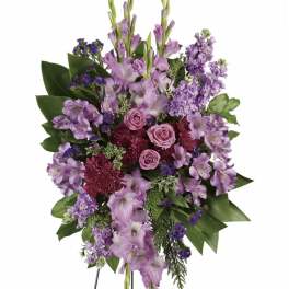 Standing spray of purple flowers with pink roses on a wire easel