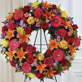 Heart-shaped floral wreath with roses, lilies, and gerbera daisies on an easel