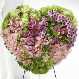 Heart-shaped floral arrangement with pink roses, carnations, and green blooms
