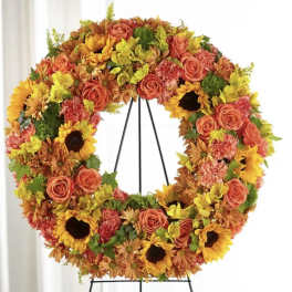 Large floral wreath with orange roses and sunflowers on a black stand