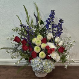 Mixed bouquet in a white vase with red, white, blue, and green flowers