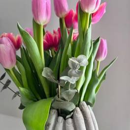 Pink tulips arranged in a gray vase with eucalyptus accents