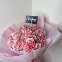 Pink bouquet of roses and carnations wrapped in pale pink paper