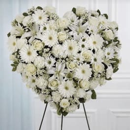 Heart-shaped standing spray of white roses, daisies, and lilies on an easel