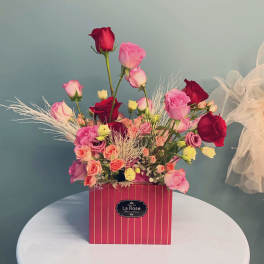 Mixed pink and red roses arranged in a striped box
