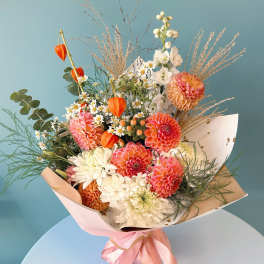 Mixed bouquet of pink, white, and orange flowers with a pink ribbon wrap