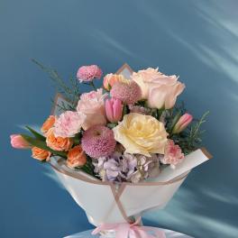 Pastel bouquet of roses, tulips, carnations, and chrysanthemums wrapped with a pink ribbon