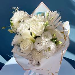 White bouquet with roses, chrysanthemums, and lisianthus in decorative wrap