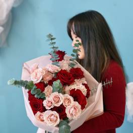Bouquet of red and blush roses wrapped in pale pink paper