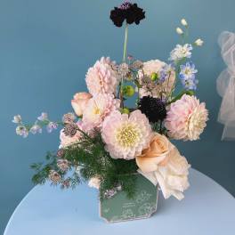 Pastel bouquet of dahlias, roses, and blue delphinium in a green box