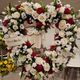 Large heart-shaped floral wreath with white and red flowers on a stand