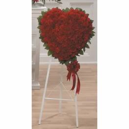Heart-shaped red floral standing spray on a white easel with ribbon