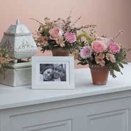 Three small floral arrangements with a framed photo and lantern centerpiece