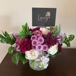 Pink, white, and purple flower arrangement in a clear glass vase
