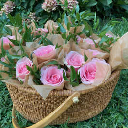 Pink roses in brown paper inside a wicker basket