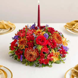 Low floral centerpiece with a red taper candle in the middle