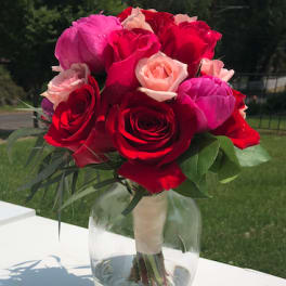 Bouquet of red, pink, and blush roses in a clear glass vase