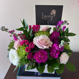 Pink and white roses with magenta blooms in a white box arrangement