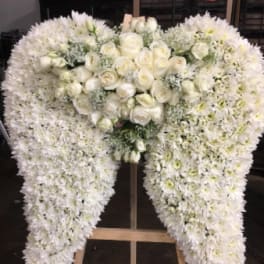 Large white floral funeral spray on a wooden easel