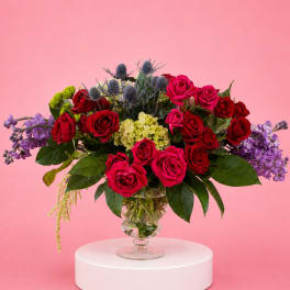 Bouquet of red and pink roses with purple flowers in a glass vase