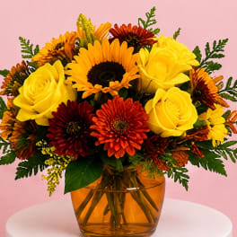 Bouquet of yellow roses and orange-red daisies in an amber glass vase