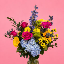 Colorful bouquet of roses, hydrangeas, and daisies in a glass vase