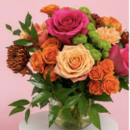 Bouquet of pink and peach roses with orange blooms in a glass vase