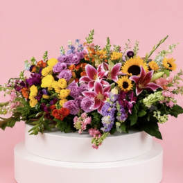 Colorful mixed flower arrangement in a white round container