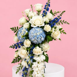 White roses and blue hydrangeas in a cascading bouquet on a pedestal