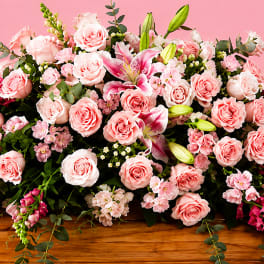 Large pink floral arrangement with roses and lilies on a wooden table