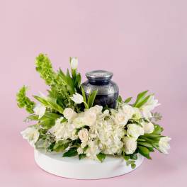 White floral arrangement with a dark urn on a round base