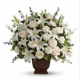 White lilies and roses arranged in a dark urn vase