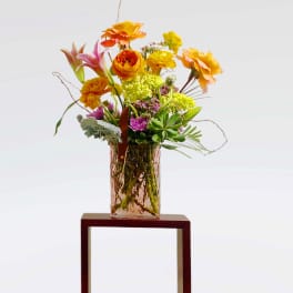 Colorful mixed bouquet in a textured glass vase on a stand
