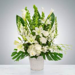 White lilies and roses arranged in a white basket