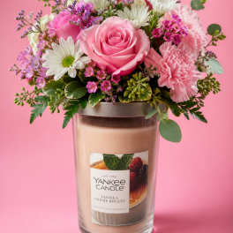 Pink and white flower arrangement in a glass candle jar