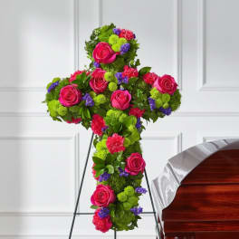 Cross-shaped floral tribute with pink roses and bright mixed blooms
