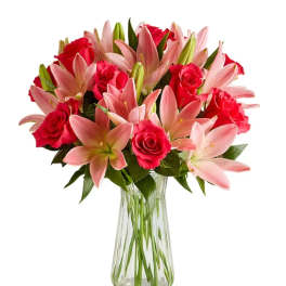 Pink lilies and red roses arranged in a clear glass vase