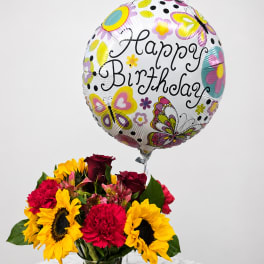 Birthday balloon above a vase of sunflowers, roses, and carnations