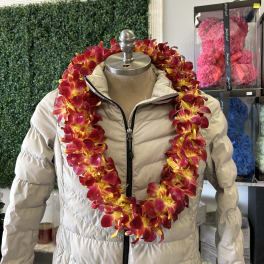 Red and yellow orchid lei draped over a beige puffer jacket on a mannequin.