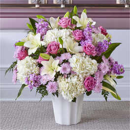 Pink roses and white lilies arranged in a white vase