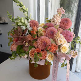 Large bouquet of pink, peach, and cream flowers in a brown box