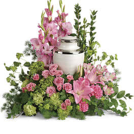 Pink flowers arranged around a white urn with silver trim