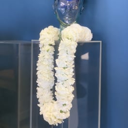 White flower garland on a clear mannequin bust with a blue graduation cap