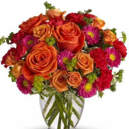 Orange roses and pink daisies in a clear glass vase