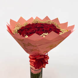 Red roses in a glass vase with pink wrapping and ribbon