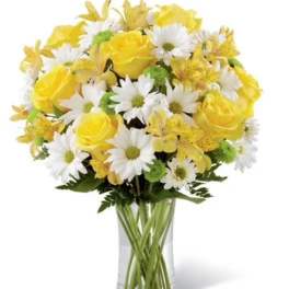 Yellow roses and white daisies in a clear glass vase