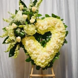 Heart-shaped floral wreath of pale yellow and cream flowers on an easel