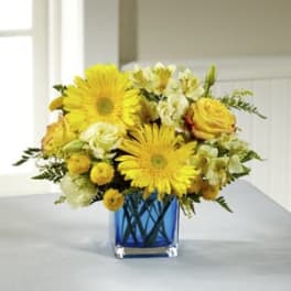 Yellow flowers arranged in a blue glass vase