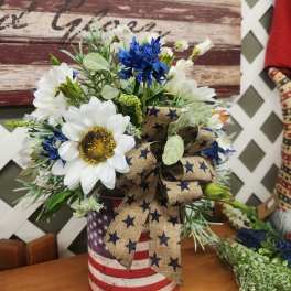 Bouquet of white and blue flowers in a patriotic tin container with a star ribbon